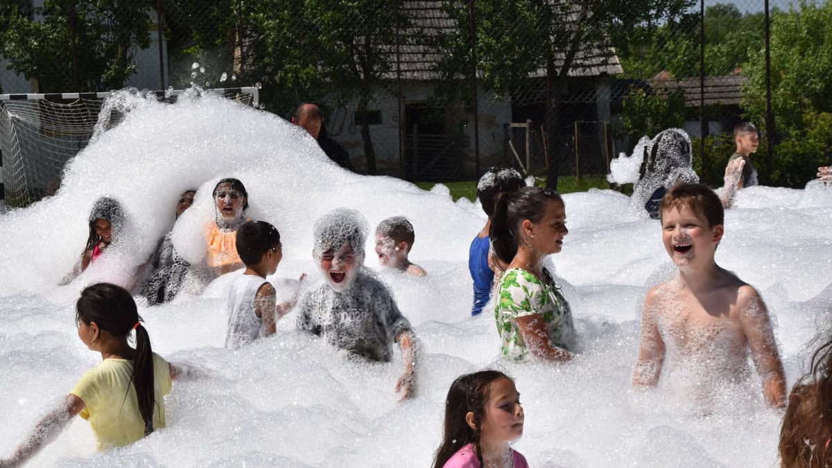 Children having fun in a foam party outdoors during summer.